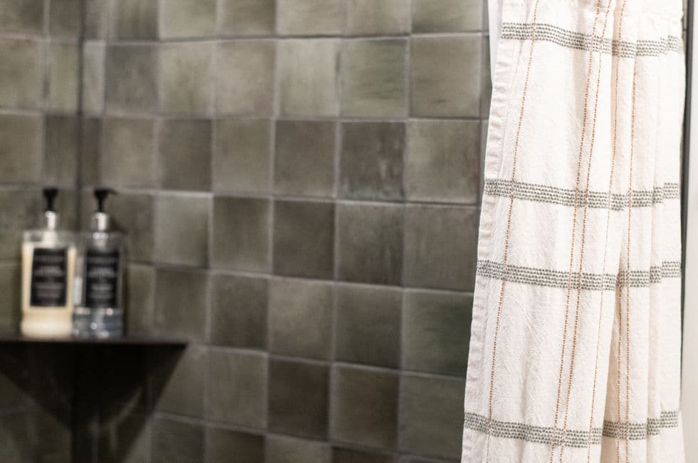 Stand up, tiled shower and bath amenities on shelf.