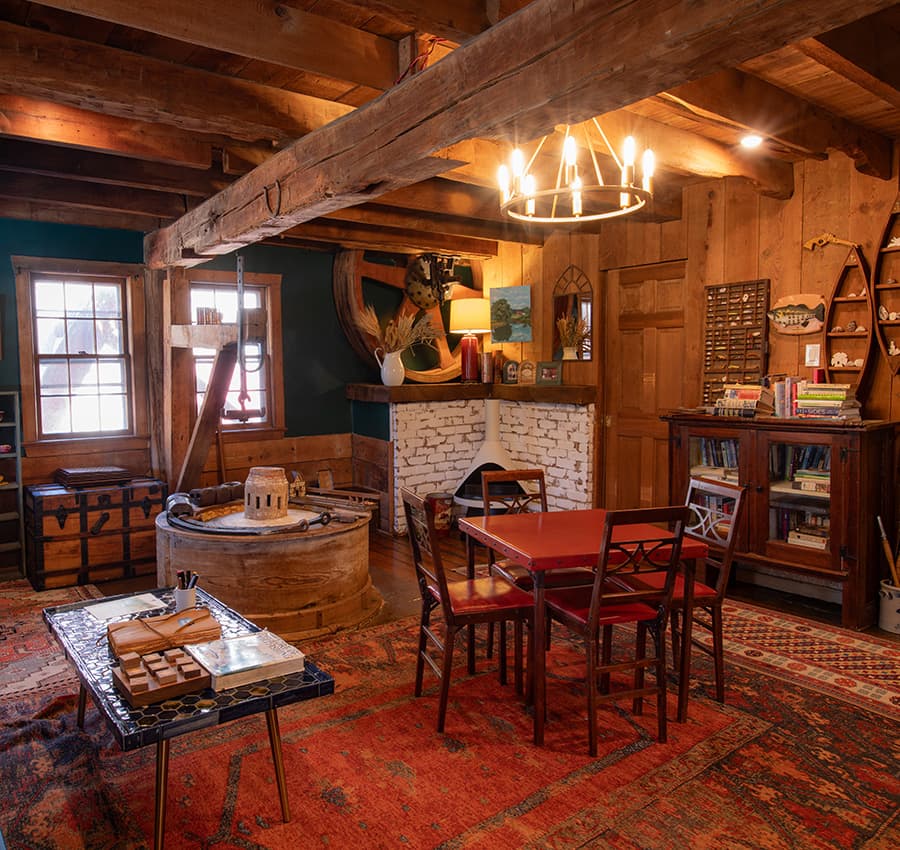 Cozy room with rustic wooden beams, a red table set, and warm decor.